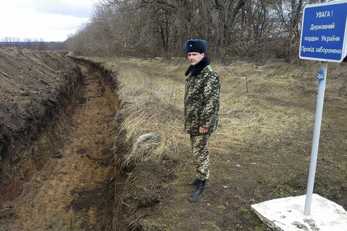 An Ukrainian army officer stands by a ditch at the Ukrainian-Russian front near the border crossing of Novoazovsk