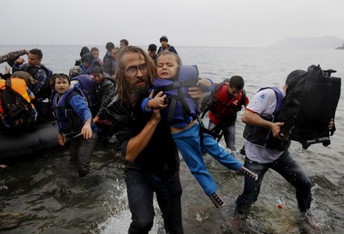 File photograph shows a volunteer carrying a Syrian refugee child off an overcrowded dinghy at a beach after the migrants crossed part of the Aegean Sea from Turkey to the Greek island of Lesbos